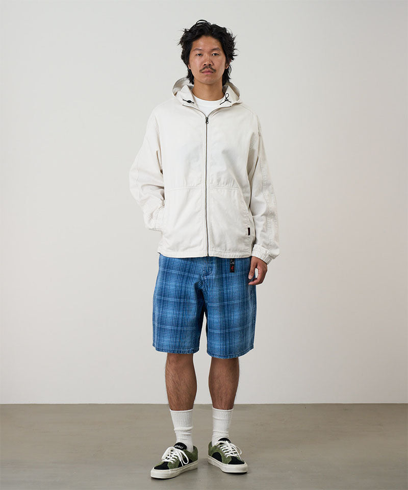 Model wearing a indego Gramicci Lagoon Short Denim Plaid and white jacket on a light-tone background.