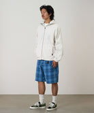 Model wearing a indego Gramicci Lagoon Short Denim Plaid and white jacket on a light-tone background.