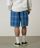 Back view of a model wearing a Gramicci indego Lagoon Short Denim Plaid against a light-tone background.