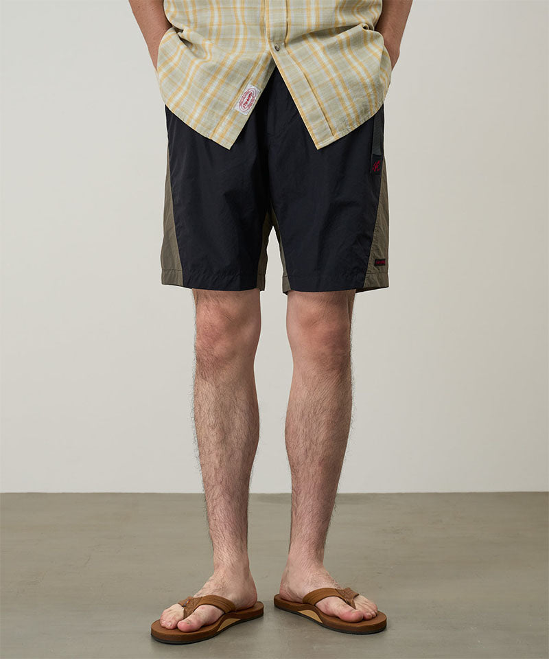 Model wearing black Gramicci Nylon Block Shorts and a yellow plaid shirt on a light-tone background.