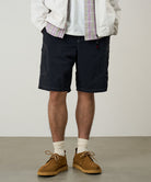 Model wearing black Gramicci Nylon Cliff Short and a white jacket on a light-tone background.