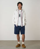 Model wearing british navy Gramicci Nylon Cliff Short and a white jacket on a light-tone background.