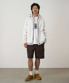 Model wearing chocolate colored Gramicci Nylon Cliff Short and a white jacket on a light-tone background.