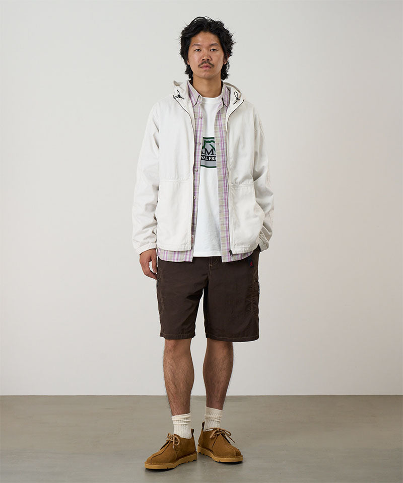 Model wearing chocolate colored Gramicci Nylon Cliff Short and a white jacket on a light-tone background.