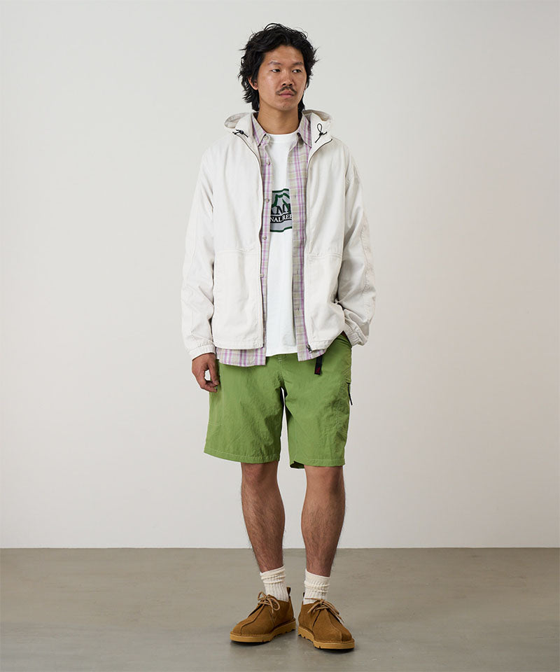 Model wearing jade green Gramicci Nylon Cliff Short and a white jacket on a light-tone background.