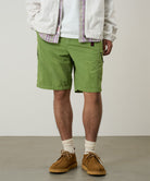 Model wearing jade green Gramicci Nylon Cliff Short and a white jacket on a light-tone background.