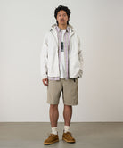 Model wearing milk tea colored Gramicci Nylon Cliff Short and a white jacket on a light-tone background.