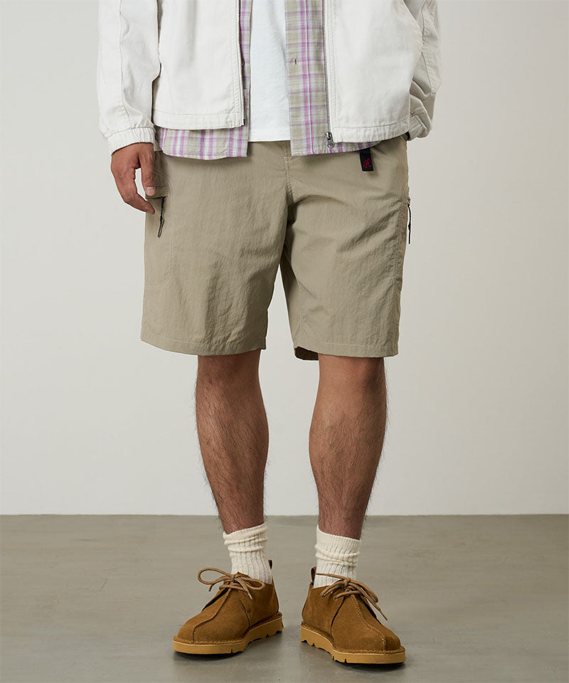 Model wearing milk tea colored Gramicci Nylon Cliff Short and a white jacket on a light-tone background.