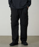 Model wearing black Gramicci Convertible Cargo Pants and a black shirt on a light-tone background.