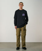 Model wearing khaki Gramicci Convertible Cargo Pants and a black shirt on a light-tone background.