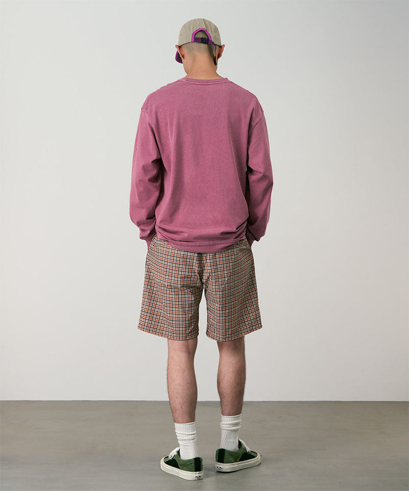 Back view of a model wearing brick check colored Gramicci Checkered Shell Shorts and a red shirt on a light-tone background.