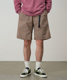 Model wearing brick check colored Gramicci Checkered Shell Shorts and a red shirt on a light-tone background.