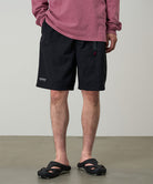 Model wearing black Gramicci Guide Shorts and a red shirt on a light-tone background.