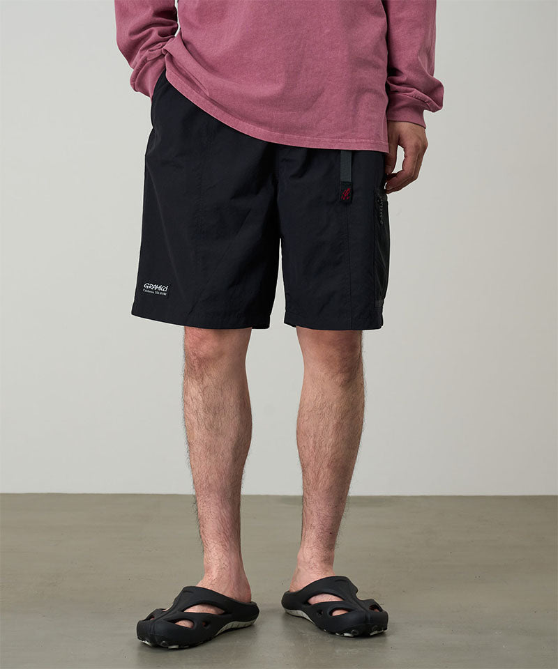 Model wearing black Gramicci Guide Shorts and a red shirt on a light-tone background.