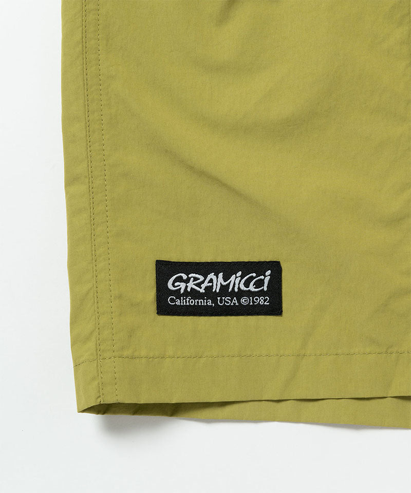 Field green Gramicci Guide Shorts hem showing the logo label on a light-tone background.