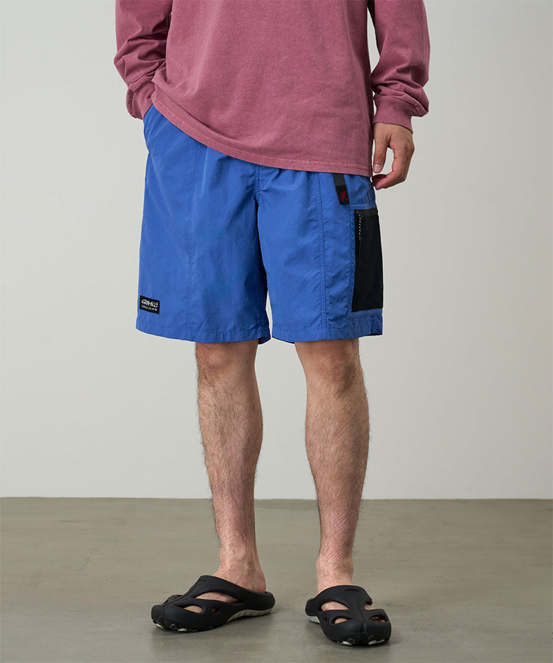 Model wearing navy blue Gramicci Guide Shorts and a red shirt on a light-tone background.