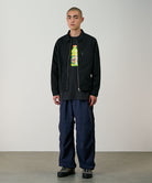Model wearing british navy Gramicci Nylon Paneled Trek Pants and a black jacket on a light-tone background.