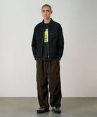 Model wearing chocolate colored Gramicci Nylon Paneled Trek Pants and a black jacket on a light-tone background.