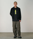 Model wearing granite colored Gramicci Nylon Paneled Trek Pants and a black jacket on a light-tone background.