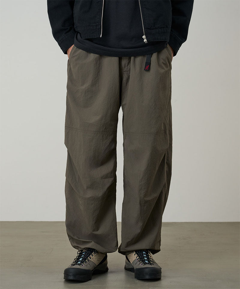 Model wearing granite colored Gramicci Nylon Paneled Trek Pants and a black jacket on a light-tone background.