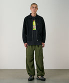 Model wearing olive Gramicci Nylon Paneled Trek Pants and a black jacket on a light-tone background.