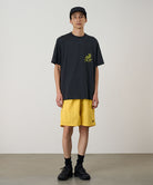 Model wearing a banana colored Gramicci Nylon Reef Short and a black shirt on a light-tone background.