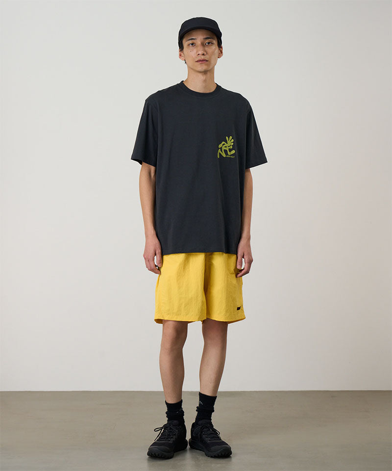 Model wearing a banana colored Gramicci Nylon Reef Short and a black shirt on a light-tone background.