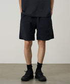 Model wearing black Gramicci Nylon Reef Shorts and a black shirt on a light-tone background.