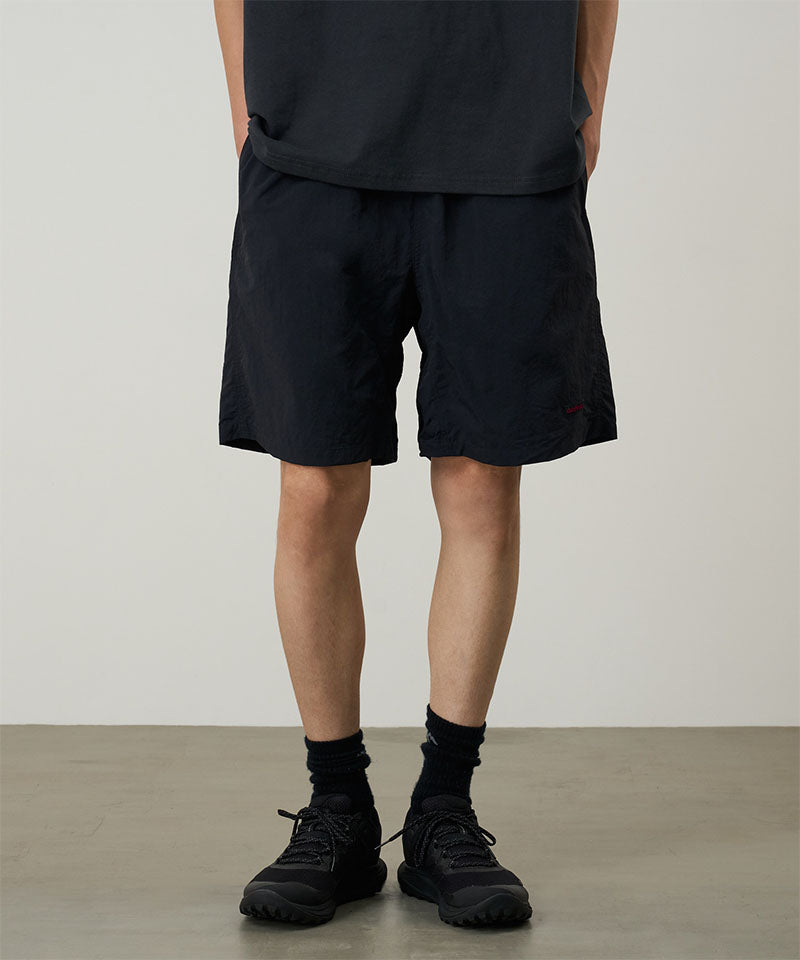 Model wearing black Gramicci Nylon Reef Shorts and a black shirt on a light-tone background.