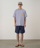 Model wearing british navy Gramicci Nylon Reef Shorts and a lavender shirt on a light-tone background.