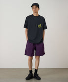 Model wearing deep purple Gramicci Nylon Reef Shorts and a black shirt on a light-tone background.