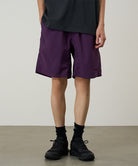 Model wearing deep purple Gramicci Nylon Reef Shorts and a black shirt on a light-tone background.