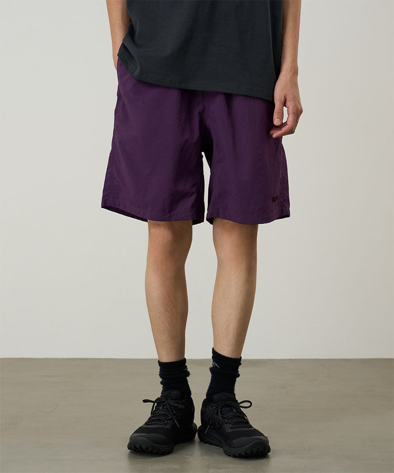 Model wearing deep purple Gramicci Nylon Reef Shorts and a black shirt on a light-tone background.