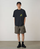 Model wearing granite colored Gramicci Nylon Reef Shorts and a black shirt on a light-tone background.