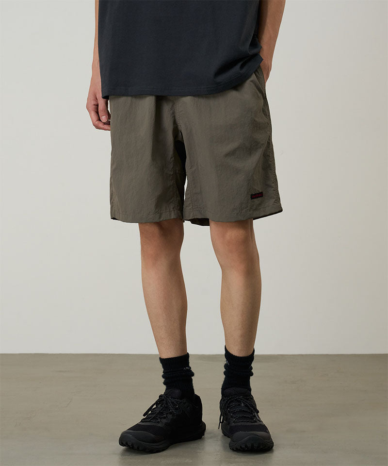 Model wearing granite colored Gramicci Nylon Reef Shorts and a black shirt on a light-tone background.
