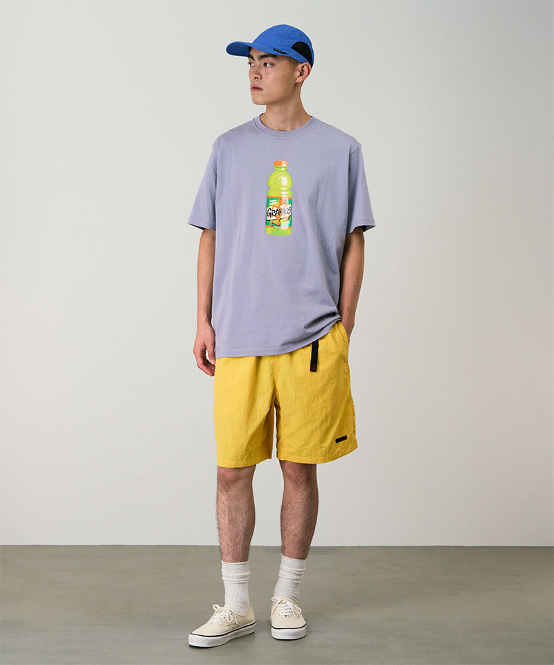 Model wearing banana colored Gramicci Nylon Packable G-Shorts and a lavender shirt on a light-tone background.