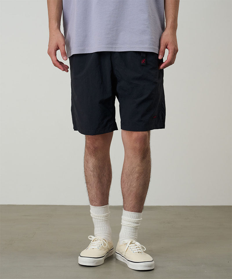 Model wearing black Gramicci Nylon Packable G-Shorts and a lavender shirt on a light-tone background.
