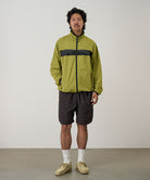 Model wearing brown leaf colored Gramicci Nylon Packable G-Short and a olive jacket on a light-tone background.