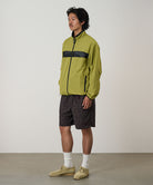 Model wearing brown leaf colored Gramicci Nylon Packable G-Short and a olive jacket on a light-tone background.