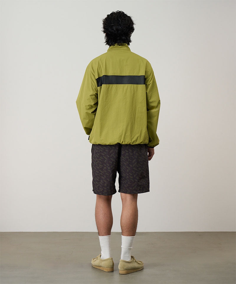 Back view of a model wearing brown leaf colored Gramicci Nylon Packable G-Short and a olive jacket on a light-tone background.