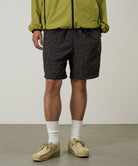 Model wearing brown leaf colored Gramicci Nylon Packable G-Short and a olive jacket on a light-tone background.