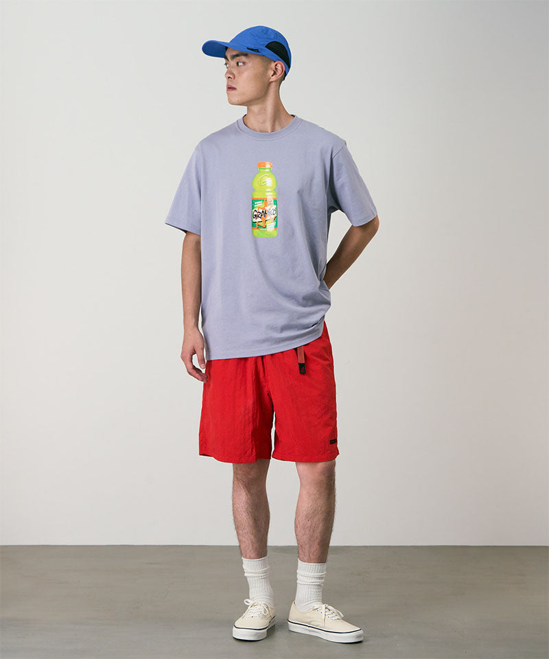 Model wearing burnt orange Gramicci Nylon Packable G-Shorts and a lavender shirt on a light-tone background.