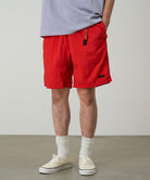 Model wearing burnt orange Gramicci Nylon Packable G-Shorts and a lavender shirt on a light-tone background.
