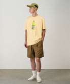 Model wearing coyote colored Gramicci Nylon Packable G-Shorts and a mango colored shirt on a light-tone background.