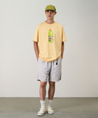 Model wearing ecru colored Gramicci Nylon Packable G-Shorts and a mango colored shirt on a light-tone background.