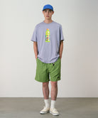 Model wearing jade green Gramicci Nylon Packable G-Shorts and a lavender shirt on a light-tone background.