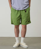 Model wearing jade green Gramicci Nylon Packable G-Shorts and a lavender shirt on a light-tone background.