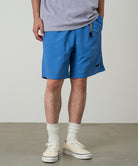 Model wearing marine colored Gramicci Nylon Packable G-Shorts and a lavender shirt on a light-tone background.
