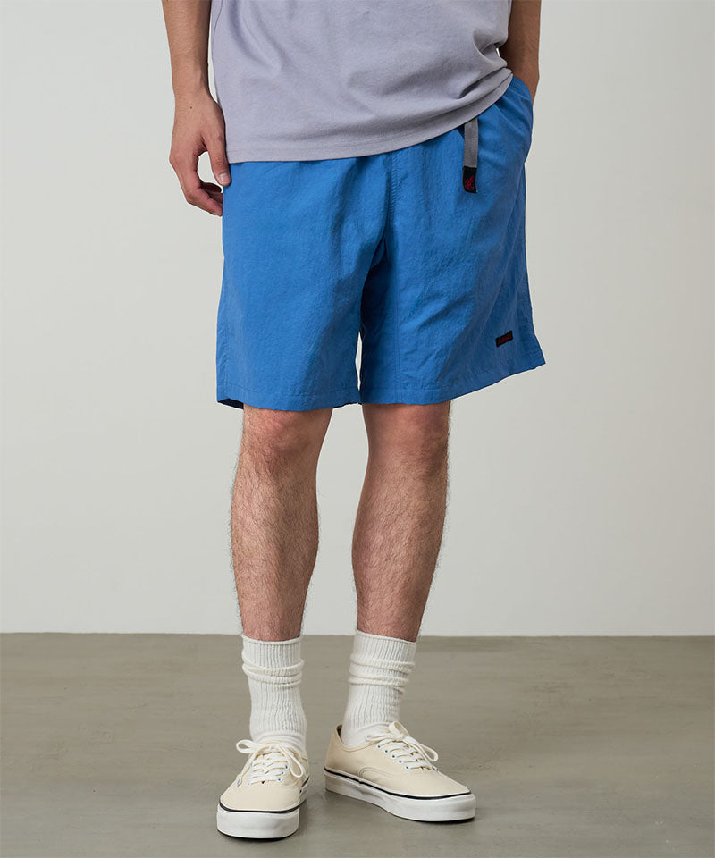 Model wearing marine colored Gramicci Nylon Packable G-Shorts and a lavender shirt on a light-tone background.