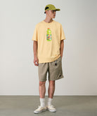 Model wearing milk tea colored Gramicci Nylon Packable G-Shorts and a mango colored shirt on a light-tone background.